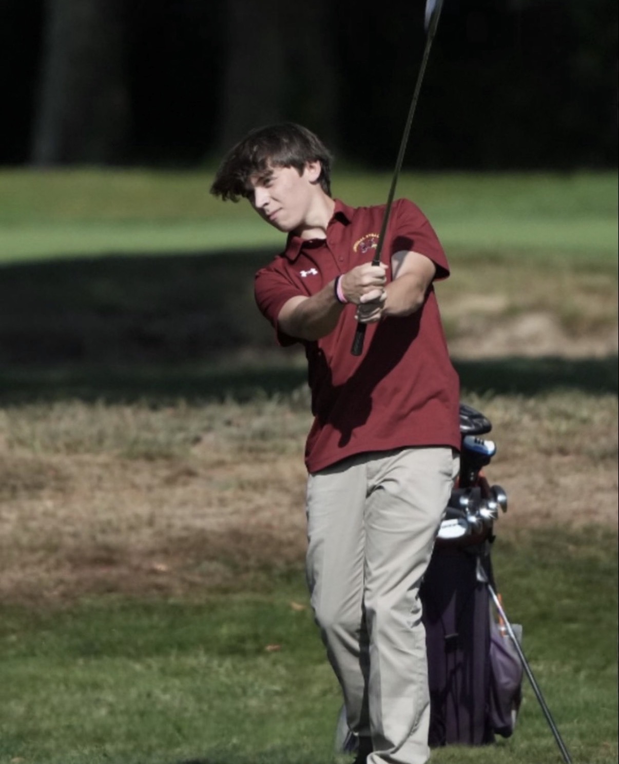Steven playing golf in high school, wearing a red shirt
