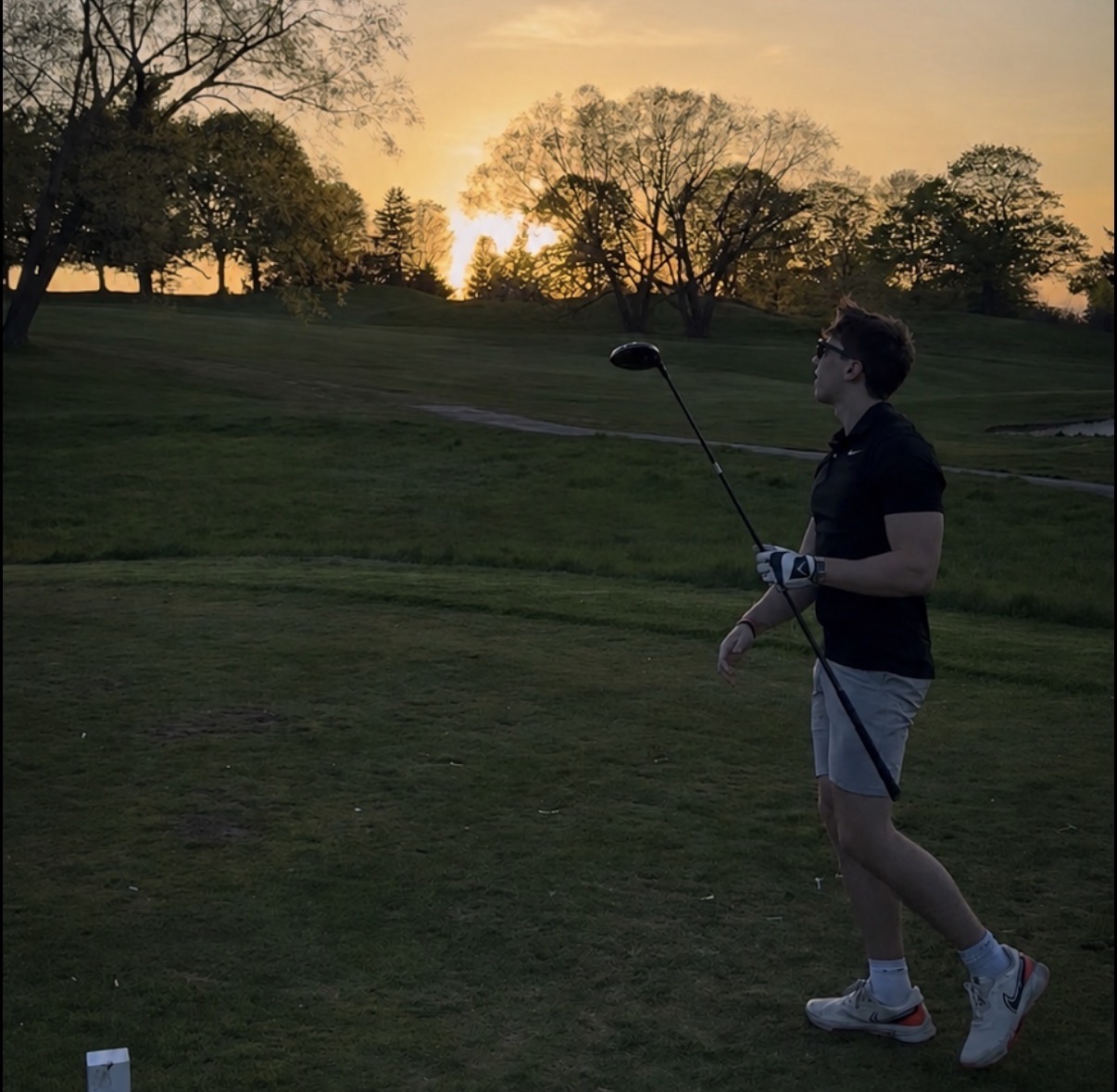 Steven holding a driver on the golf course at sunset